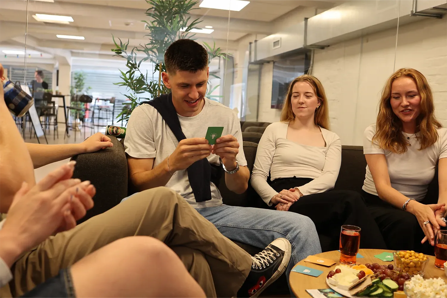 Young people having fun playing social shuffle card game at home reading